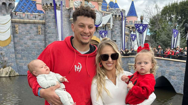 Patrick Mahomes con su esposa y dos hijas posan ante el castillo de Disneylandia.